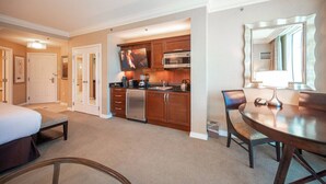 A hotel room with a bed, a dining table, a kitchen area, and a large mirror. - *No Resort Fee*MGM StripView*Jacuzzi*F1 Trackview* (Las Vegas)