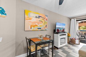 A modern living room with a dining area, a flat-screen TV, and a large abstract painting. - Oceanview, Pools, Hot tub, Indoor pool, 2 Beds (Myrtle Beach)
