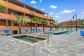 A hotel with a pool area, multiple lounge chairs, and a building with balconies. - Oceanview, Pools, Hot tub, Indoor pool, 2 Beds (Myrtle Beach)