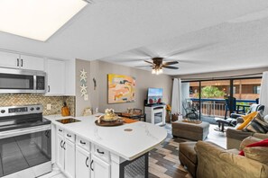 A modern kitchen with a central island, a dining area with a television, and a balcony with outdoor furniture. - Oceanview, Pools, Hot tub, Indoor pool, 2 Beds (Myrtle Beach)
