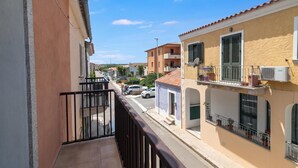 A residential street with houses, a balcony, and a clear sky.