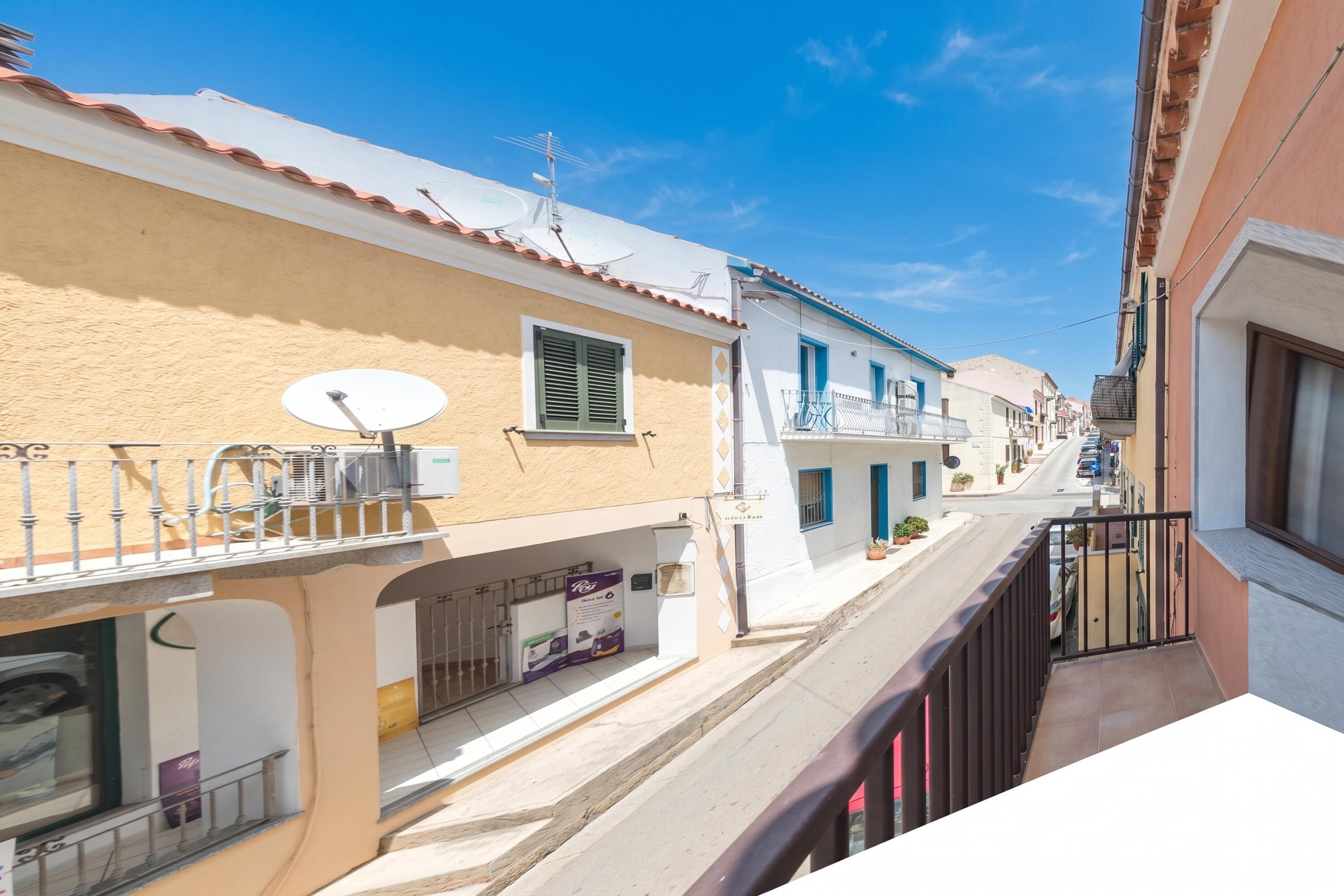 Una calle estrecha con edificios, balcones y antenas parabólicas.
