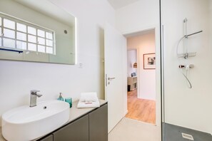 Ein Badezimmer mit weißem Waschbecken, Spiegel und Dusche.