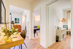 Ein zeitgemäßer Wohnraum mit Esstisch aus Holz, einer Couch und einem Bücherregal.