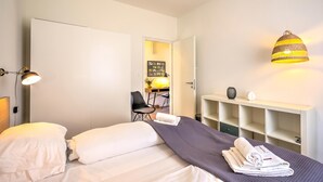 Quarto de hotel moderno com cama, abajur e luminária pendente.
