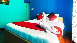 Una cama con una colcha roja y blanca, dos almohadas rojas y una toalla blanca colgada del lado.