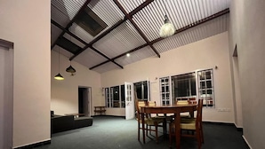 Una habitación espaciosa con techo alto, una mesa de comedor con sillas y ventanas amplias.