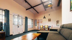 Una habitación amplia con techo alto, un sofá, una mesa de madera y una zona de comedor con sillas.