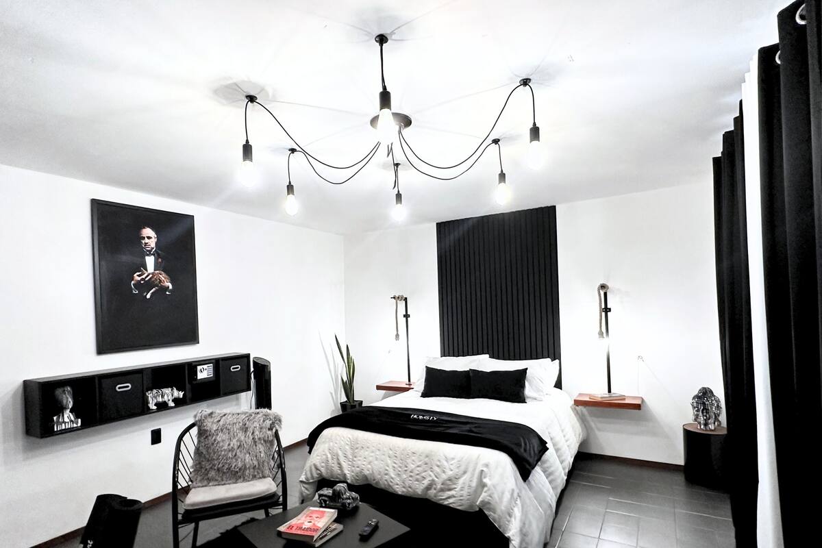 A modern bedroom with a bed, a chair, a desk, and a ceiling fan.