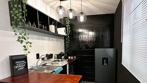 Una cocina compacta con una mesa de madera, un lavamanos y un refrigerador.