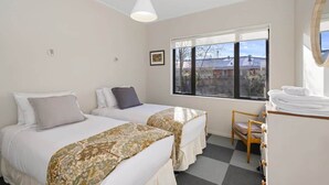 Hotellihuone, jossa on kaksi sänkyä, ikkuna, josta on näkymä, tuoli ja työpöytä, jonka päällä on pyyhkeitä.