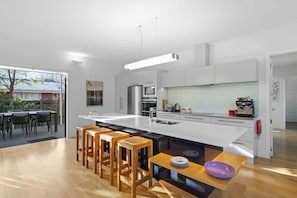 A modern kitchen with a central island, bar stools, and a dining area with a table and chairs.
