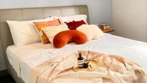 Un lit bien fait, avec une couvre-lit de couleur claire et un plaid décoratif.