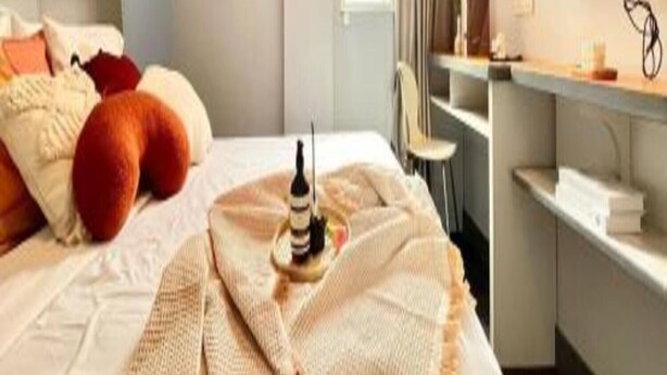 Une chambre d’hôtel avec un lit, un bureau, une télévision et une fenêtre avec des rideaux.