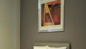 Une chambre d’hôtel avec un lit, deux tables de chevet et un tableau encadré au mur.