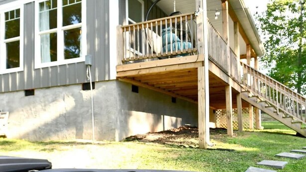 Une maison avec un jacuzzi en premier plan, une terrasse couverte et un escalier menant à un deuxième étage.