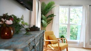 Une pièce avec une chaise en bois, une grande fenêtre et une plante.