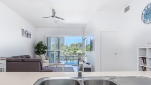 Une cuisine moderne dotée d’un évier à deux bacs, d’un ventilateur de plafond et offrant une vue sur le balcon extérieur.