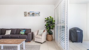 Un salon comprenant un canapé, un fauteuil, une table basse et une plante en pot.