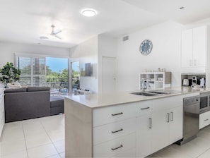 Enjoy a comfortable stay in this apartment with a spacious kitchen, central island, and large window offering a view of the surrounding greenery.