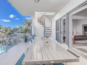 Enjoy the view from this balcony with a wooden table and chairs, offering a glimpse of the surrounding landscape.
