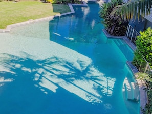 Guests can enjoy a refreshing swim in the pool surrounded by lush greenery and a well-manicured lawn.
