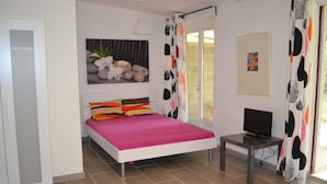 A bedroom with a bed, a TV, and a painting on the wall. - Studio Bird de mer (Canale-di-Verde)