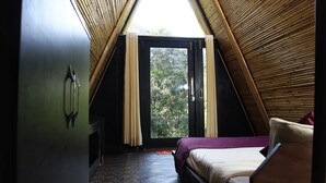 A bedroom with a sloped ceiling, a bed, a window, and a door. - Beyond Stay Ananhyam Resort Sattal (Noida)