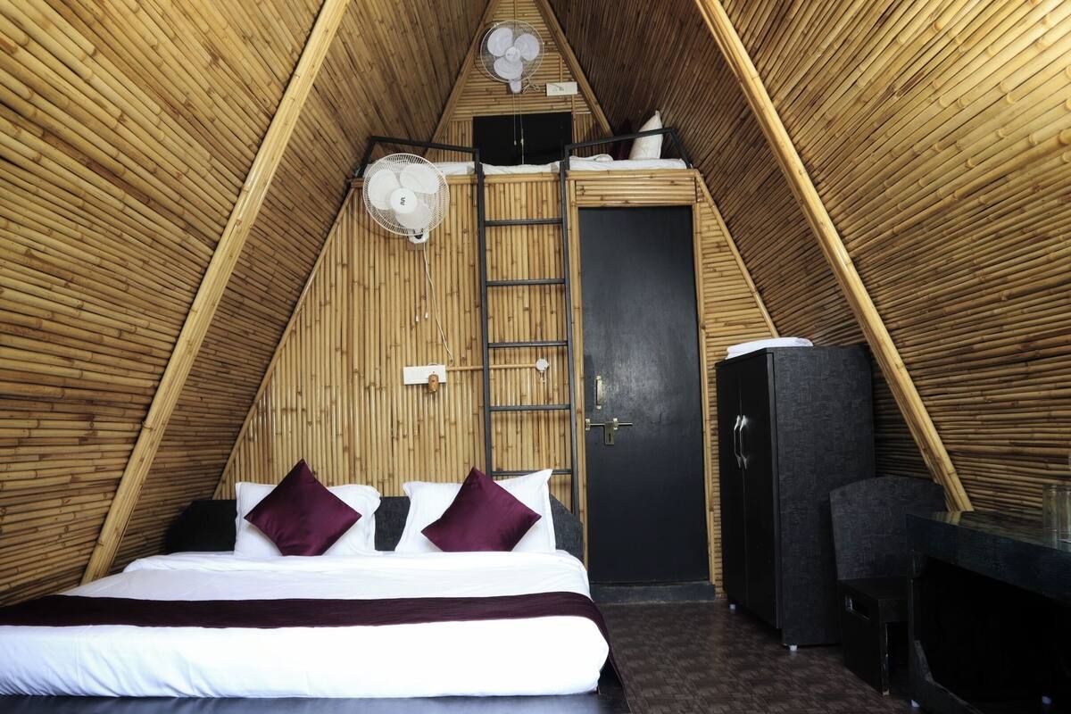 Ein raumförmiger Raum mit Bett, einer Leiter, einer Tür und einem kleinen Tisch.