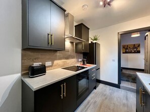 A modern kitchen with dark cabinetry, a stainless steel range hood, and a countertop toaster.