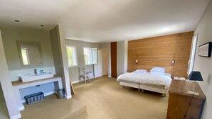 Ein Schlafzimmer mit einem hölzernen Kopfende, einem Bett, einem Nachttisch, einer Lampe und einem Fenster.