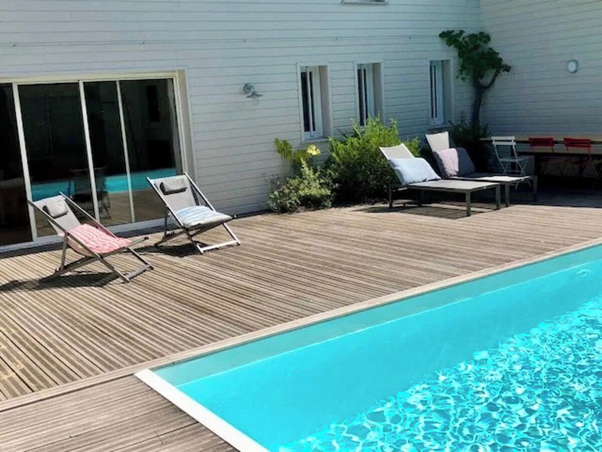 Una piscina con lettini e un solarium in legno.
