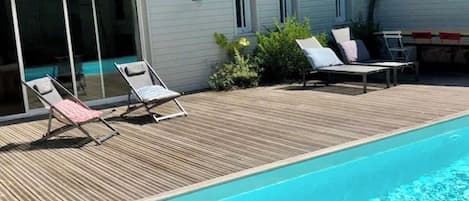 Una piscina con sillas de descanso y una terraza de madera.