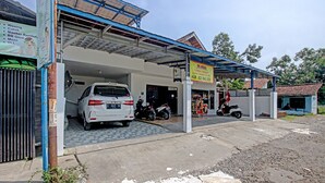 A car wash facility with a covered entrance, a motorcycle parked outside, and a signboard advertising services. - Hotel O Kedai Cinta Guest House (West Cirebon)
