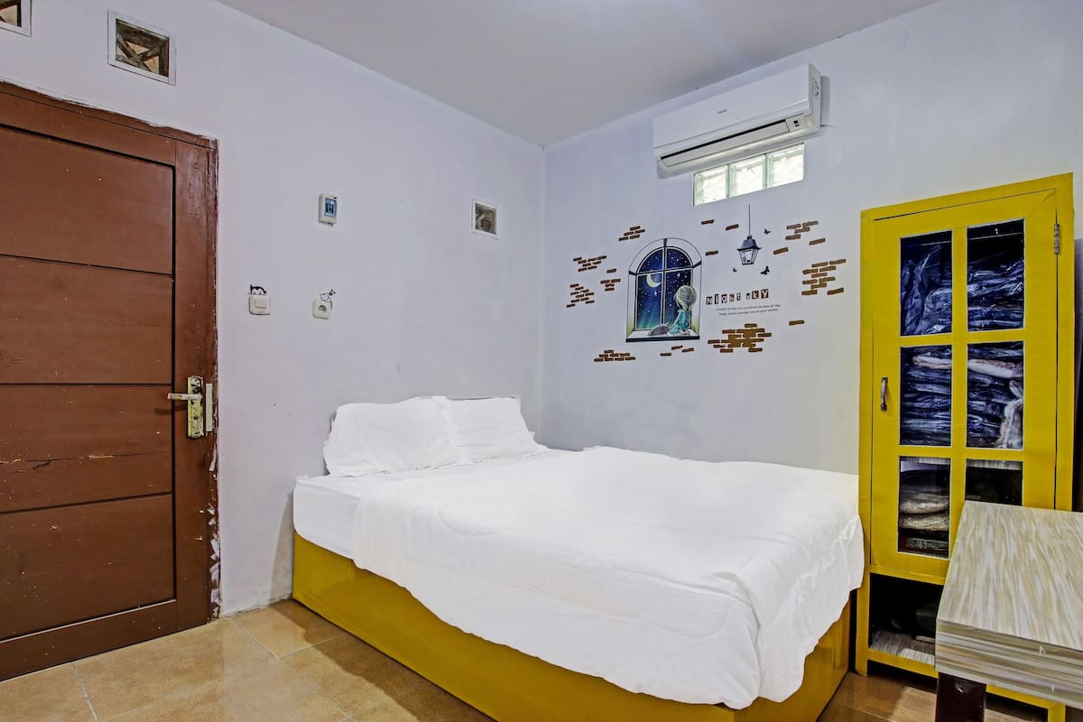 Ein Zimmer mit einem Bett, einem gelben Schrank und einer Tür.