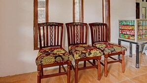 Three wooden chairs with floral upholstery, a tiled floor, and a refrigerator stocked with beverages. - Hotel O Kedai Cinta Guest House (West Cirebon)