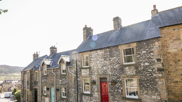 A row of stone buildings with traditional architecture, including chimneys and windows. - Knoll Cottage (Bakewell)