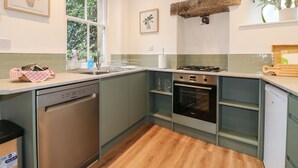 A modern kitchen with a dishwasher, oven, and a window providing natural light. - Knoll Cottage (Bakewell)