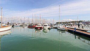 Een jachthaven met diverse boten afgemeerd, kalm water en een heldere lucht.