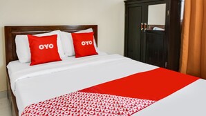 A hotel room with a bed, two red pillows with the word "OYO" on them, a white bedspread, and a red blanket with the same word. - OYO Life  91569 Omah Wijaya Kusuma Syariah (Asrikaton)