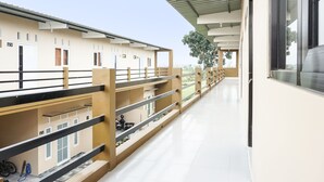 A modern building with multiple balconies, a covered walkway, and a clear view of the surrounding area. - OYO Life  91569 Omah Wijaya Kusuma Syariah (Asrikaton)