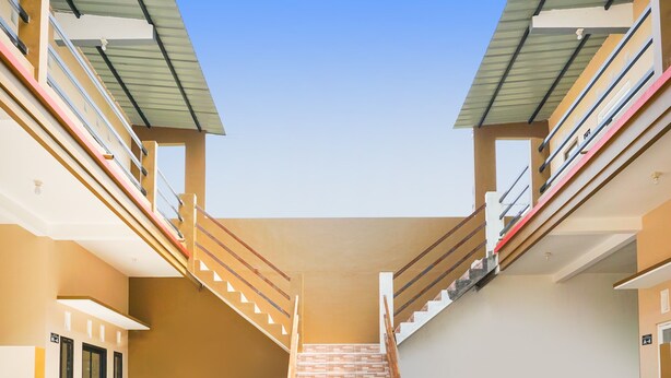 A multi-level building with a central staircase, balconies, and a clear sky. - OYO Life  91569 Omah Wijaya Kusuma Syariah (Asrikaton)
