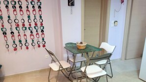 A dining area with a green table, four white chairs, and a basket on the table. - Quiet apartment in Marathonas - 5 min from the beach! (Μαραθώνας)