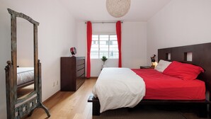 A bedroom with a wooden bed, a dresser, a mirror, and a hanging light fixture. - Casa de Chiles - the best spot in Cuauhtémoc (Mexico City)
