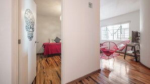 A room with a bed, a red chair, a desk with a computer, and a window with a view. - Casa de Chiles - the best spot in Cuauhtémoc (Mexico City)