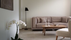 Un salon avec un canapé beige, une table basse, un lampadaire et une orchidée en pot.