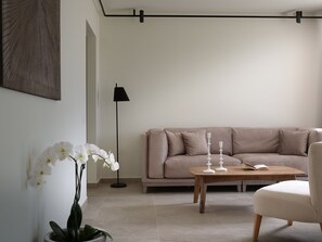 Un salon avec un canapé beige, une table basse, un lampadaire et une orchidée en pot.