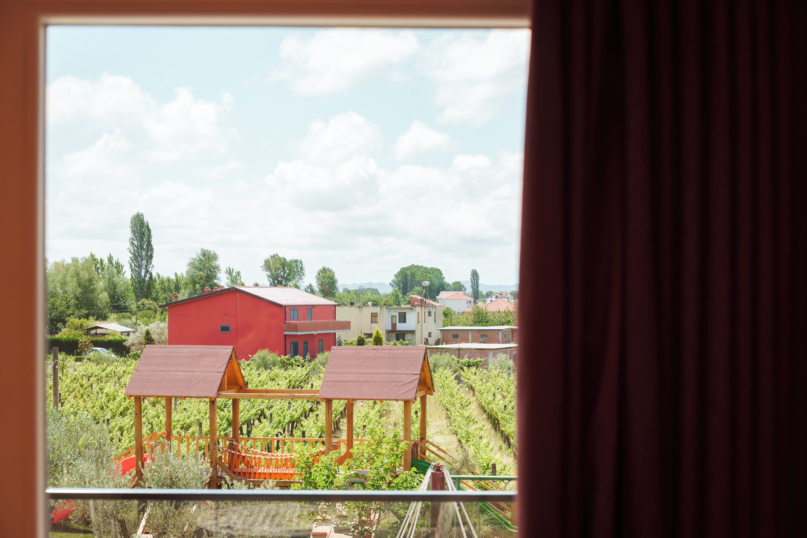 Viñedo con un edificio rojo y una estructura de madera al frente.