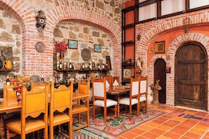 Comedor con paredes de ladrillo, mobiliario de madera y suelo de baldosas.