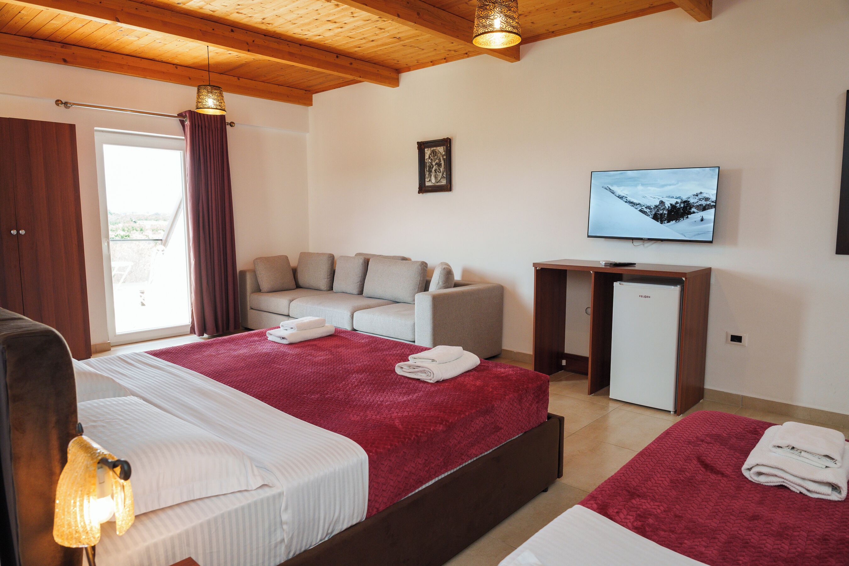 Een hotelkamer met een bed, een bank, een televisie en een koelkast.